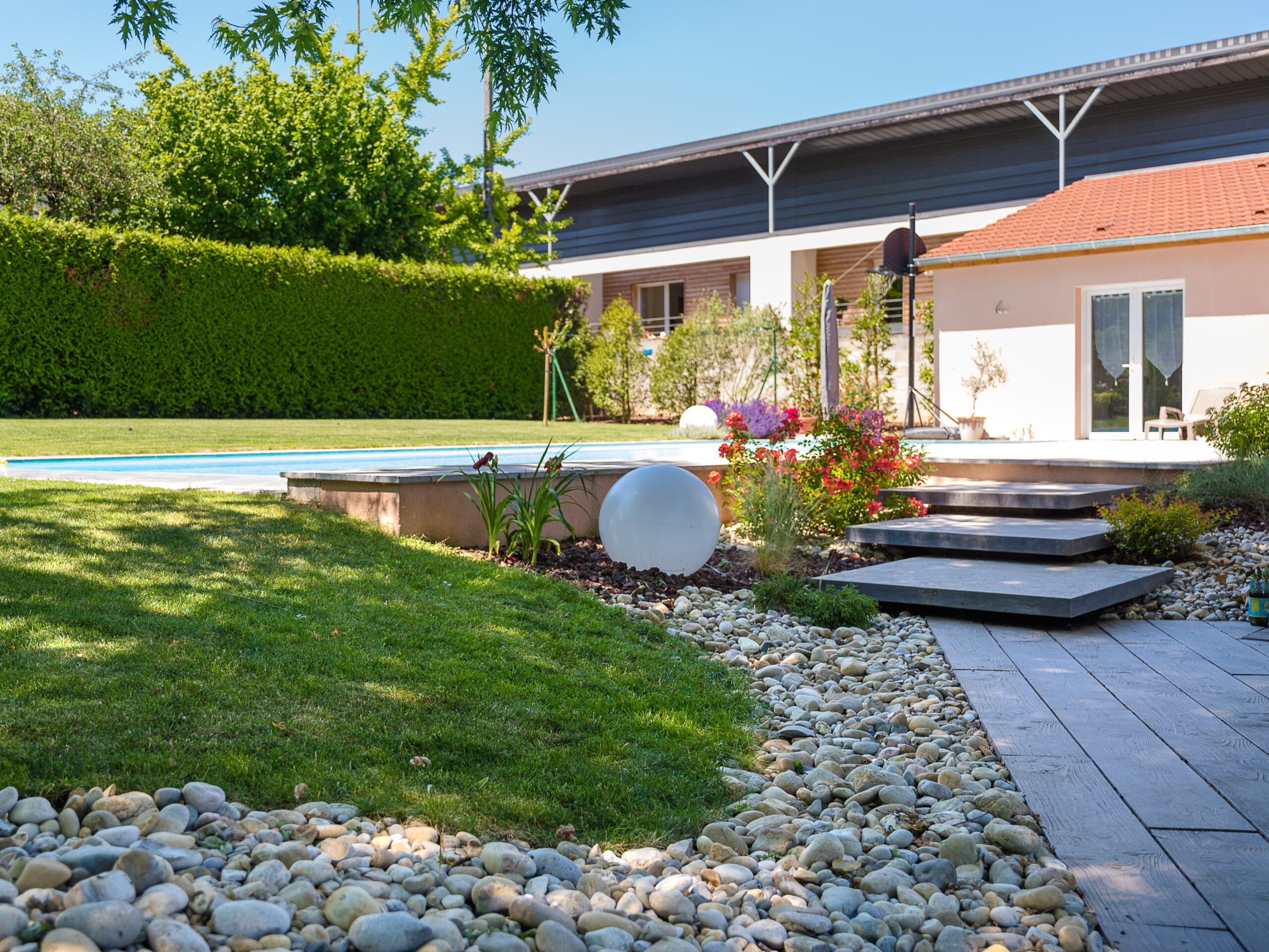 Jardin paysager avec piscine, terrasse composite et massif de galets — Chalon-sur-Saône, Saône-et-Loire — Perret Paysage & Piscine