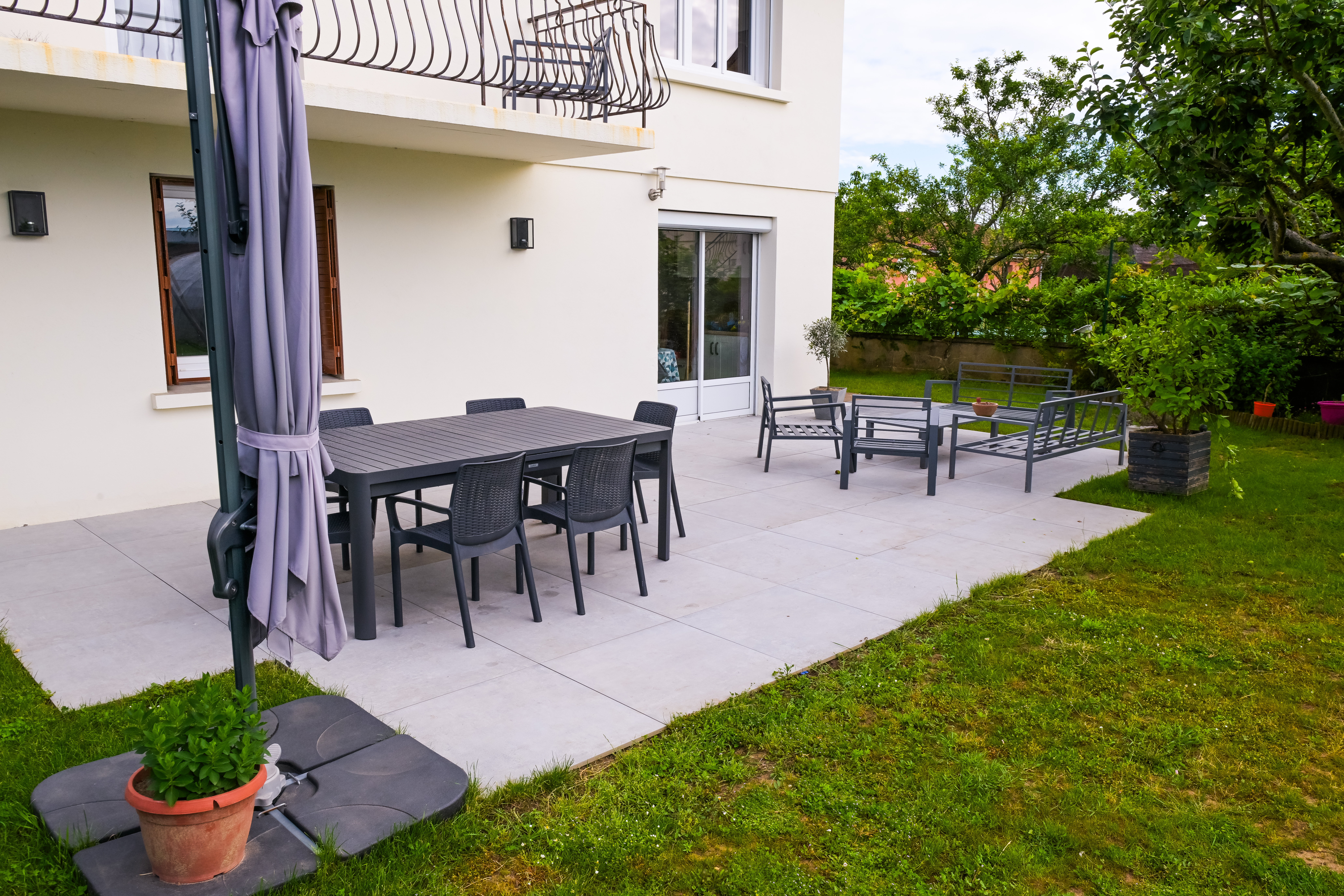Terrasse en dallage clair avec salon de jardin et table à manger extérieure — Chalon-sur-Saône, Saône-et-Loire — Perret Paysage & Piscine