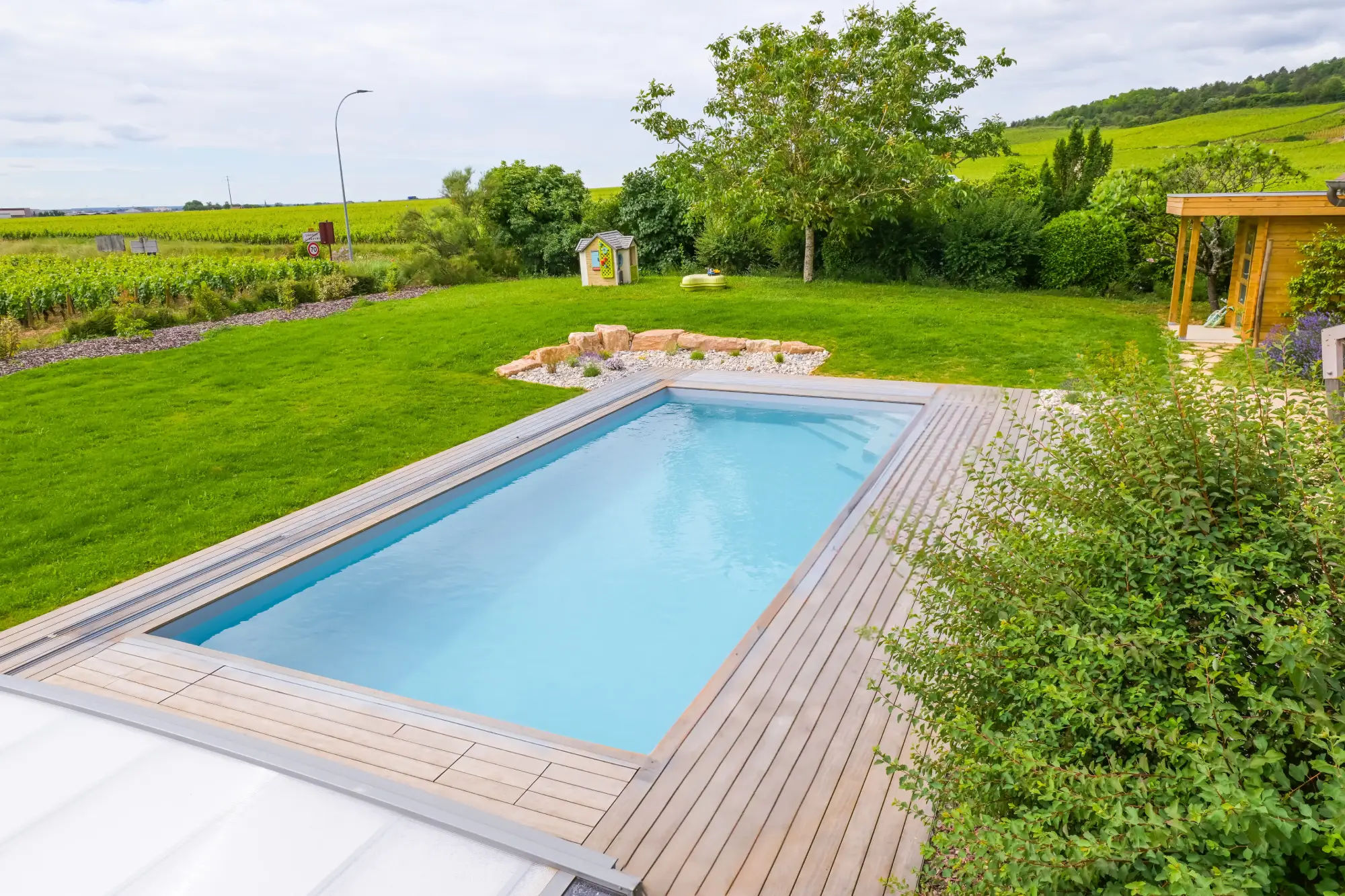 (Stephen M. - Savigny-les-Beaune) : Piscine enterrée en bois avec massif de rocaille et vue sur le vignoble — Savigny-lès-Beaune, Côte-d’Or — Perret Paysage & Piscine