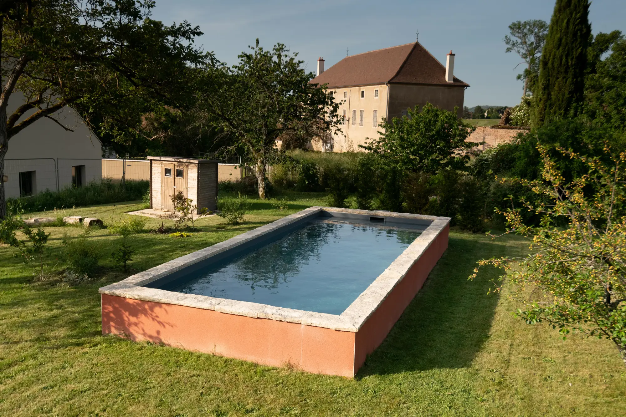(Claude L. - Chassagne-Montrachet) : Piscine semi-enterrée à margelle en pierre installée dans un jardin engazonné — Chassagne-Montrachet, Côte-d’Or — Perret Paysage & Piscine